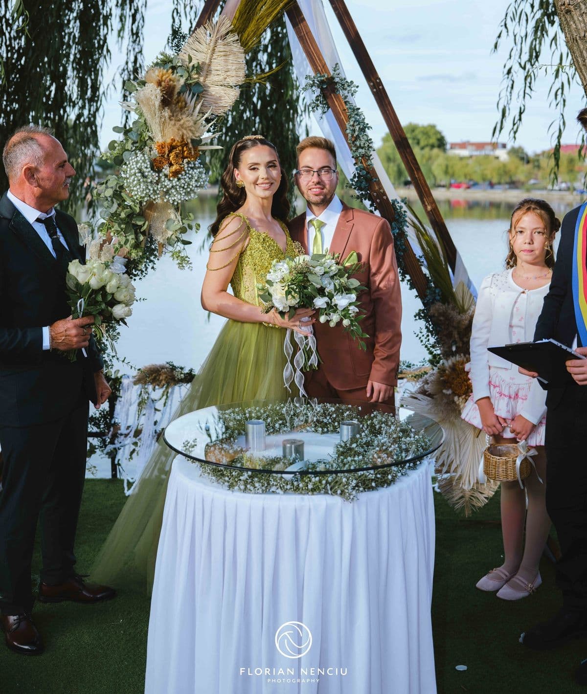 Mirii la masa de ceremonie, cu nașii alături, sub arcada de la lac