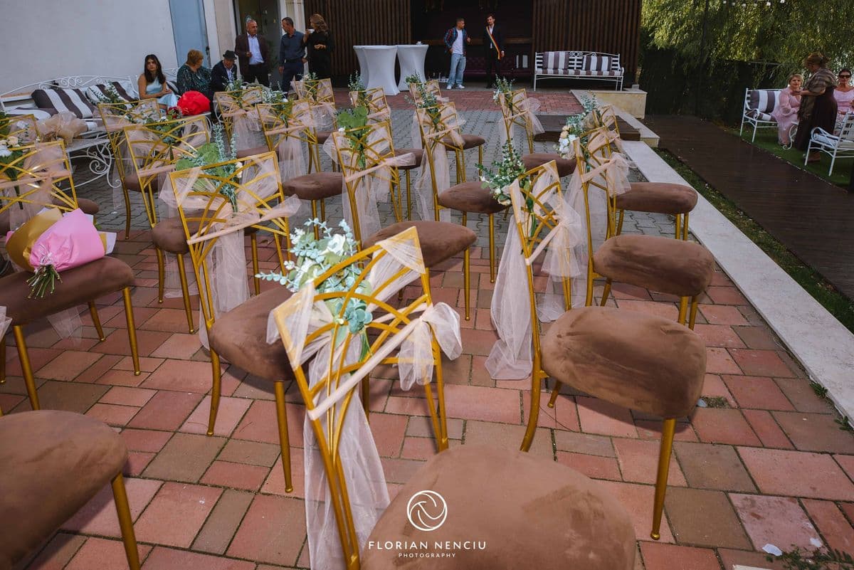 Rândurile de scaune decorate pentru ceremonie (invitații se văd în fundal, mici)